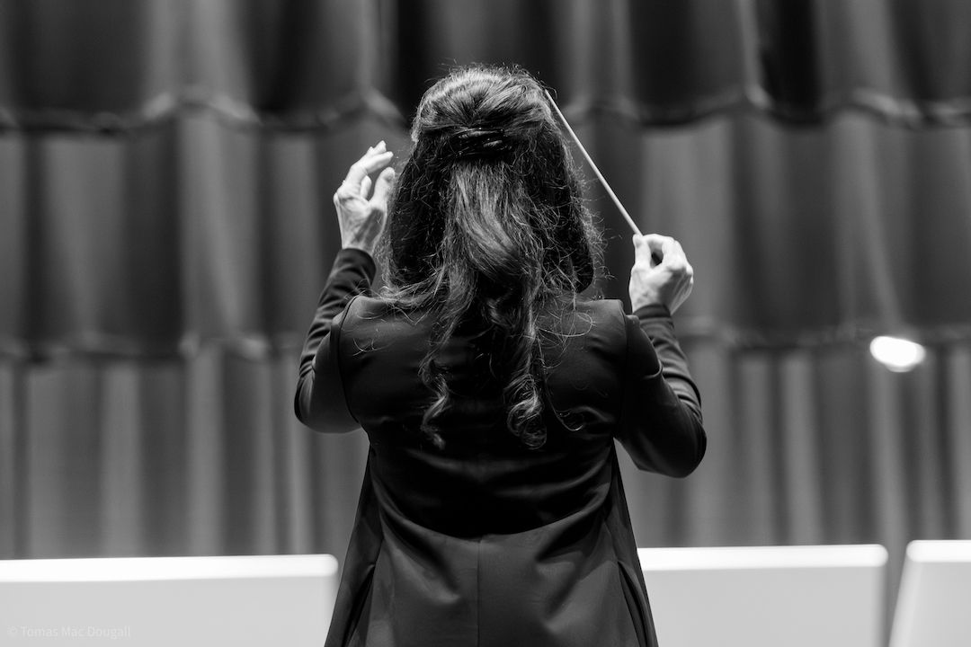 Andrea DeRenzis Strauss conducting Tara Winds, baton raised, viewed from behind