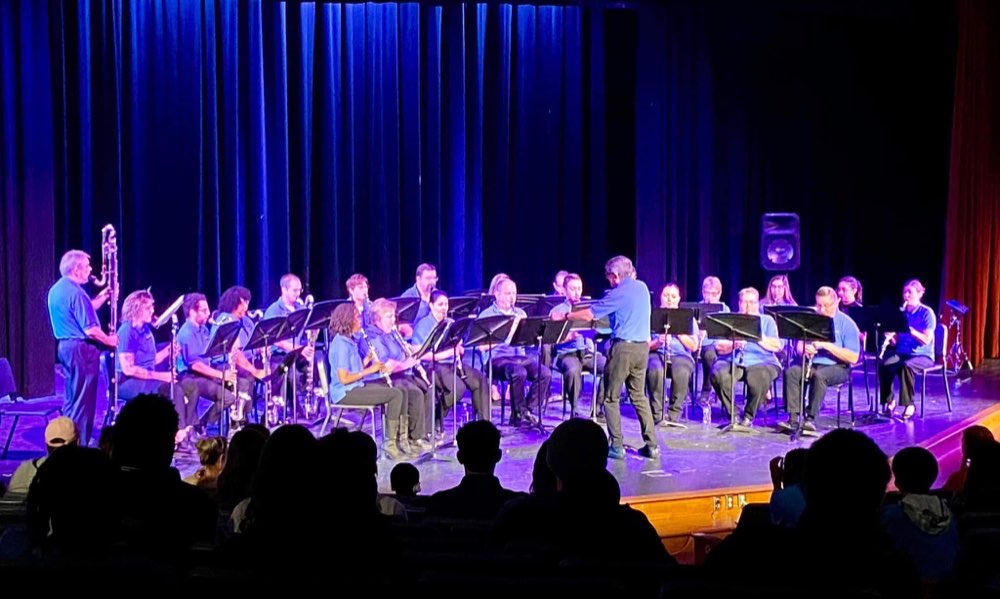The Clarinet Choir performing under blue stage light to a seated audience