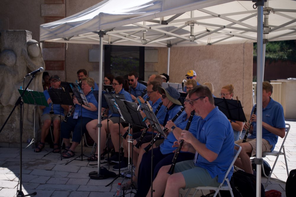 The Clarinet Choir playing outdoors in the shade of a white canopy